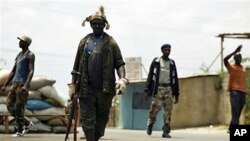 Fighters opposed to Laurent Gbagbo's bid to cling to power man a roadblock in the Abobo district of Abidjan, Ivory Coast Saturday, Mar12 2011