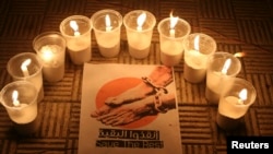 FILE - Lit candles are placed by activists around a placard during a vigil in solidarity with the detainees in Syrian prisons at Aleppo's Salaheddine neighborhood, Jan. 26, 2015. 