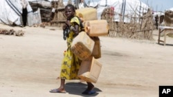 In this photo taken Sunday Aug. 28, 2016 a girl displaced by Islamist Extremists carries empty plastic containers at a camp Maiduguri, Nigeria.