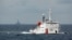 FILE - A Chinese Coast Guard vessel, with the disputed oil rig in the background, is seen in the South China Sea, June 13, 2014.