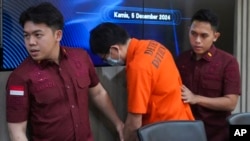 印尼移民警察把最近被逮捕的中國公民髕振興(音譯)帶到雅加達的一次記者會，這名男子因據稱為網絡賭博犯罪團夥洗錢而被中國通緝並列入國際刑警組織紅通名單。 (2024年12月5日)