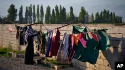 FILE - A Syrian refugee hangs her family's laundry outside her tent at a refugee camp in the town of Bar Elias, Lebanon, on July 7, 2022. Lebanon says it currently hosts around 2 million people from neighboring Syria — the world's highest number of refugees per capita.