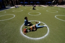 FILE - Kyree Kayoshi, his dog Kumi, and Miranda De Llano use circles marked for social distancing at the Pearl Brewery in San Antonio, March 3, 2021. What will happen when restrictive, virus-related rules for interaction are all gone?
