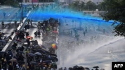 FILE - In this Sept. 15, 2019, photo, police fire water cannons at pro-democracy protesters outside the government headquarters in Hong Kong.