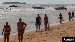 Tourists walk on a beach in Pattaya, June 6, 2014.