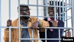 FILE - Opposition leaders Kizza Besigye and Hajj Obeid Lutale stand in a steel dock at the Uganda Military General Court in Makindye, a suburb of Kampala, Uganda, on Dec. 2, 2024.