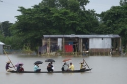 People ride on a boat through flooded waters in Sunamgong, Bangladesh, July 14, 2020.