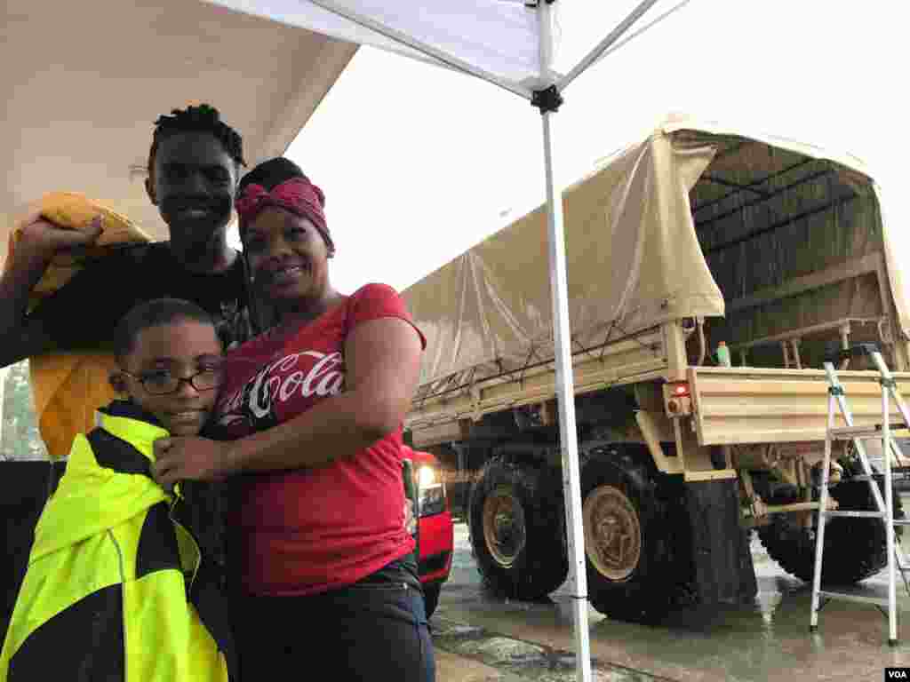 Lakwesha Davis and sons Terminus Brothers Jr., 14, and Trestian Woodard, 7, wait for a friend after being rescued from their flooded Greenbriar Colony neighborhood in Houston, Texas, Aug. 27, 2107. (C. Mendoza/VOA)