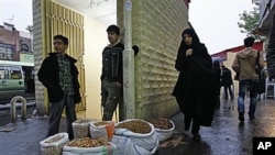 Pedestrians walk past vendor Amir Jamali, center, as he waits for customers after islamic leaders began cutting an estimated $100 billion a year in government subsidies for fuel and food, on a street in downtown Tehran, Iran, Nov 2010 (file photo)
