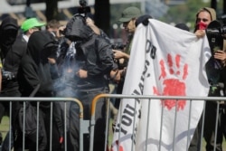 FILE - Antifa counterprotesters, rallying against right-wing group Patriot Prayer, light a smoke grenade in Portland, Oregon, Sept. 10, 2017.