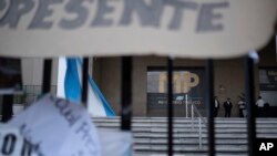 Personal de seguridad custodia una puerta mientras manifestantes protestan frente a la Fiscalía General de la República en la Ciudad de Guatemala, el miércoles 18 de octubre de 2023.