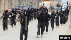 Fighters of al-Qaida-linked Islamic State of Iraq and the Levant carry their weapons during a parade at the Syrian town of Tel Abyad, near the border with Turkey, Jan. 2, 2014.