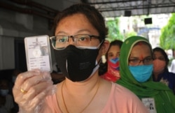Indian women voters wearing face masks as a precaution against the coronavirus wait outside a polling station to cast their votes during the last phase of West Bengal state elections in Kolkata, April 29, 2021.