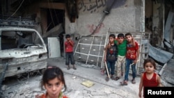 Children are seen near rubble of damaged buildings in the eastern Damascus suburb of Ghouta, Syria, July 17, 2017.