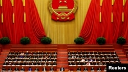 China's President Xi Jinping and other delegates listen as China's Premier Li Keqiang (not pictured) delivers a government work report during the opening session of the National People's Congress (NPC) at the Great Hall of the People in Beijing. 