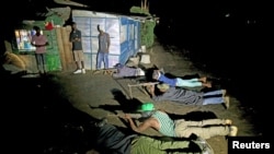 Armed vigilantes lay on the ground with their rifles as they patrol in the center of Bujumbura, Burundi, Nov. 20, 2015.