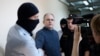 FILE - Paul Whelan, a former U.S. Marine, second left, who was arrested for alleged spying in Moscow at the end of 2018, is escorted by Federal Security Service officers to a court room in Moscow, Russia, Aug. 23, 2019.