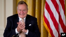 Former President George H. W. Bush applauds as he participated in a ceremony to present the 5,000th Daily Point of Light Award to Floyd Hammer and Kathy Hamilton, of Union, Iowa, in the East Room of the White House in Washington, July 15, 2013.
