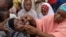 FILE- In this April 13, 2014 file photo, an unidentified health official administers a polio vaccine to a child in Kawo Kano, Nigeria. 