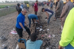 Investigators examine the scene after eight rail cars flipped over April 18, 2021, in Egypt's Qalyubia province. (Hamada Elrasam/VOA)