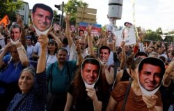 FILE - Supporters of Turkey's main pro-Kurdish Peoples' Democratic Party (HDP) hold masks of their jailed former leader and presidential candidate Selahattin Demirtas during a rally in Ankara, June 19, 2018.
