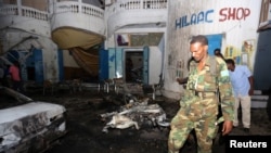 A Somali soldier inspects the scene of an explosion outside the Oromo restaurant in Mogadishu October 12, 2014.