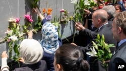 Turkey's president Rejep Tayyip Erdogan (C-R) pays his respect as he with others decorate the vehicle carrying the remains of 33 victims of the Srebrenica massacre, in Sarajevo, Bosnia, July 9, 2019. 