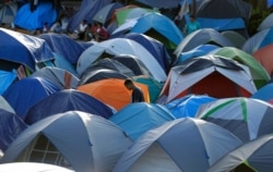 FILE - A migrant walks through a refugee camp in Matamoros, Mexico, Nov. 5, 2019. Mexican authorities are working to close the improvised camp along the Rio Grande that has housed thousands of asylum-seekers.