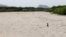 An Iranian girl walks across the Zayandeh Rud river in Isfahan, now dry because of water extraction before it reaches the city, April 11, 2018.