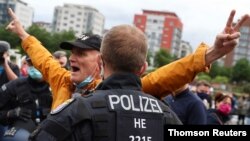 A police officer detains a protester who took off his mask during a protest against the government's restrictions following the coronavirus disease outbreak, in front of the headquarters of the European Central Bank, in Frankfurt, Germany, May 23, 2020.