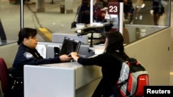 FILE - A foreign airline passenger hands travel documents to a Customs and Border Protection Officer at Hartsfield-Jackson International Airport in Atlanta, Georgia, Jan. 5, 2004. 