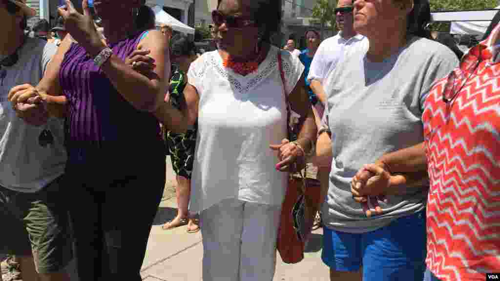 Mourners hold hands during prayers outside Emanuel AME Church, Charleston, June 20, 2015. (Amanda Scott/VOA)