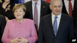 German Chancellor Angela Merkel, left, and the Prime Minister of Israel Benjamin Netanyahu, right, pose with government members for a group photo during a one day German-Israeli governmental meeting at the chancellery in Berlin, Germany, Feb. 16, 2016.