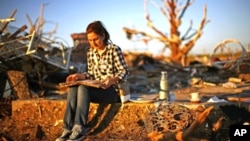 Chanell Gonzalez looks through her grandfather&#39;s yearbook which she found in his destroyed home in Joplin, Missouri, May 26, 2011
