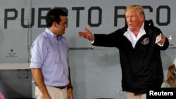 FILE - U.S. President Donald Trump talks with Puerto Rico Governor Ricardo Rossello (L) in a hangar at Muniz Air National Guard Base in Carolina, Puerto Rico, Oct. 3, 2017.