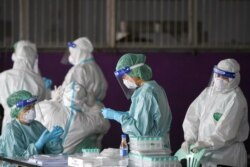 FILE - Healthcare workers get ready to collect samples during proactive testing of migrant workers at their work place, amid the spread of the COVID-19 outbreak in Samut Sakhon province in Thailand, Jan. 27, 2021.