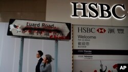 Des passants devant un panneau vandalisé près d'une succursale de la banque HSBC endommagée par des manifestants pro-démocratie à Hong Kong, le 4 janvier 2020. (AP)