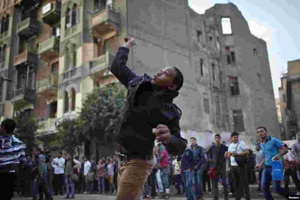 A protester throws stones at riot police during clashes at Tahrir Square in Cairo November 26, 2012.