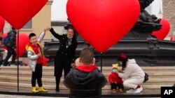 北京的一名家长和孩子一起游玩拍照。（2021年2月13日）