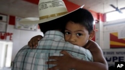 FILE - Miguel, 3, clings to his father, Miguel, an undocumented migrant, in San Juan, Texas, Aug. 27, 2010. Miguel and his wife, who remain in the U.S. as undocumented migrants, have two children born in the U.S. 