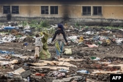 A woman accompanied by her children picks through discarded items in the area where a camp for internally displaced persons once stood before it was destroyed, in Goma on Feb. 1, 2025.