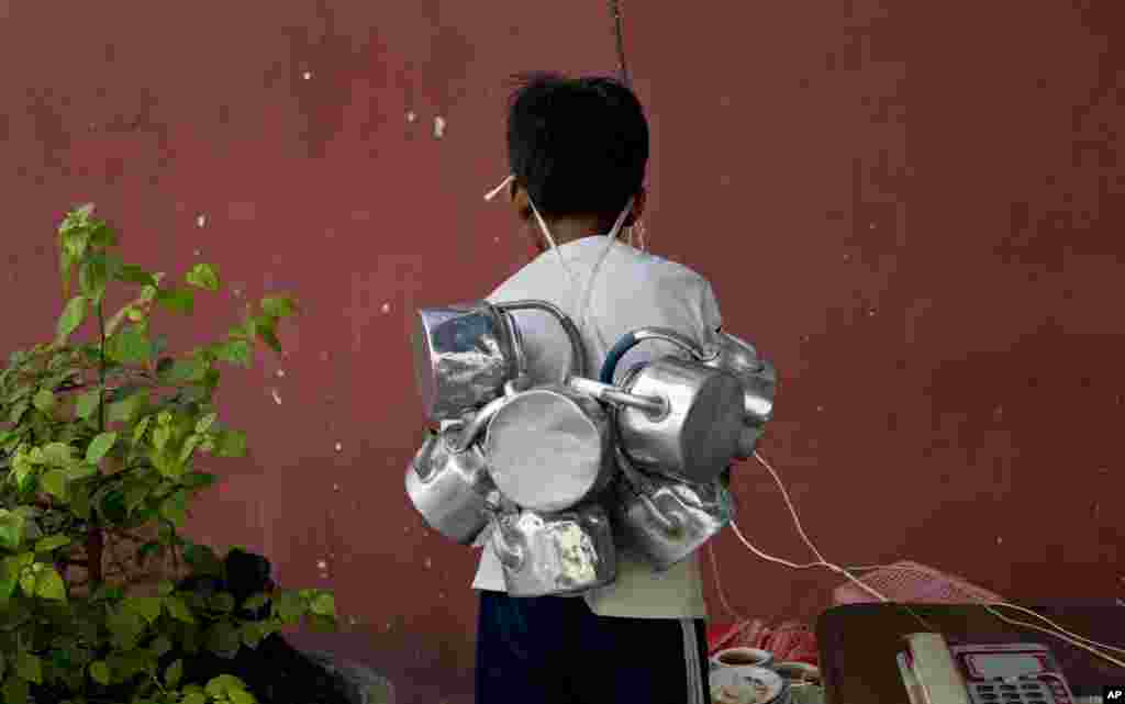 Seorang anak laki-laki Myanmar membawa ketel-ketel tempat teh yang kosong di Rangoon.