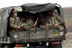 Ethnic Armenian soldiers sit in a military truck on a road during the withdrawal of troops from the separatist region of Nagorno-Karabakh, Nov. 19, 2020.