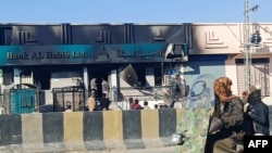 পাকিস্তানের বেলুচিস্তান প্রদেশের কালাত জেলায় জঙ্গিদের আগুনে পুড়ে যাওয়া একটি ব্যাংকের পাশ দিয়ে যাচ্ছে মানুষ। হামলায় ১৮ সেনা নিহত হয়েছে বলে জানিয়েছে পুলিশ ও সেনাবাহিনী। ১ ফেব্রুয়ারি ২০২৫। 