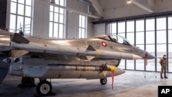 A military police officer stands in front of a Danish Royal Air Force F-16 fighter jet during the welcome ceremony at the Siauliai air force base some 230 km (144 miles) east of the capital Vilnius, Lithuania, Jan. 28, 2022.