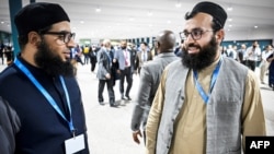 Hamed Safi (R), a member of Afghanistan's delegation, talks to his colleague during a break in a plenary session of the COP29 Summit in Baku on Nov. 11, 2024, on the opening day of the 2024 UN Climate Change Conference. 