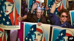 FILE - In this Feb. 19, 2017, photo, people carry posters during a rally against President Donald Trump's executive order banning travel from six Muslim-majority nations, in New York's Times Square.