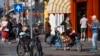 FILE - People, some wearing face masks, observe social distancing to prevent the spread of the coronavirus when standing in line to buy traditional King's Day pastry in Amsterdam Netherlands, April 27, 2020. 