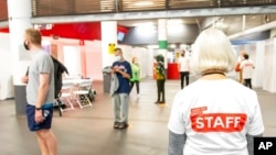 FILE - People queue at a mass coronavirus vaccination center held in Arsenal's Emirates Stadium, in north London, June 25, 2021. 