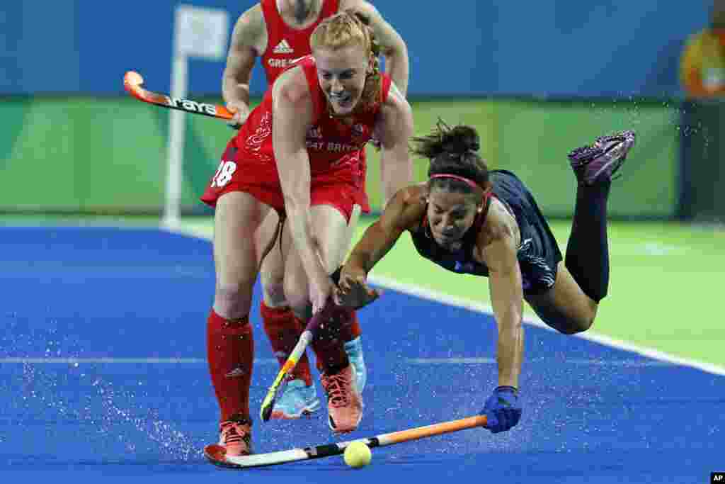 United States' Melissa Gonzalez, right, falls while fights for the ball with Britain's Nicola White during a women's field hockey match at the 2016 Summer Olympics in Rio de Janeiro, Brazil, Aug. 13, 2016. 